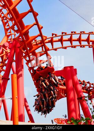 Energylandia, Pologne - 23 août 2024 : une image en gros plan d'une piste de montagnes russes rouge et du ciel bleu et des gens excités qui apprécient la balade. Banque D'Images