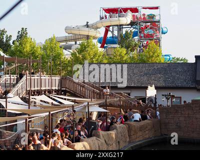 Energylandia, Pologne - 23 août 2024 : parc d'attractions avec des foules de touristes, des files d'attente, des arbres verts et de grands toboggans aquatiques en arrière-plan Banque D'Images