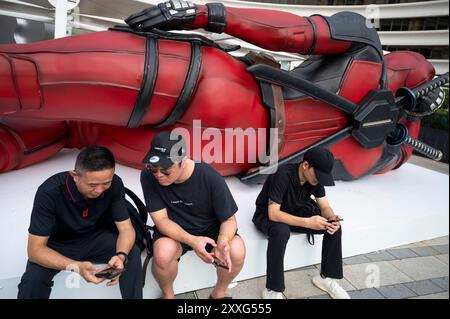 Hong Kong, Chine. 18 août 2024. Les habitants et les touristes posent pour des photos avec l'installation de 8 mètres du personnage de Deadpool de Marvel, mis en place pour promouvoir le nouveau film « Deadpool & Wolverine » sorti sous Disney à Hong Kong. (Crédit image : © Miguel Candela/SOPA images via ZUMA Press Wire) USAGE ÉDITORIAL SEULEMENT! Non destiné à UN USAGE commercial ! Banque D'Images