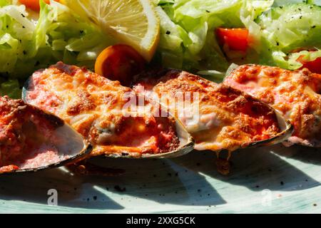 moules cuites au four avec du caviar masago et du fromage sur une assiette blanche avec du citron Banque D'Images