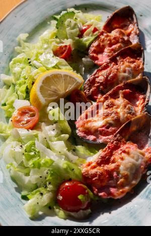 moules cuites au four avec du caviar masago et du fromage sur une assiette blanche avec du citron Banque D'Images