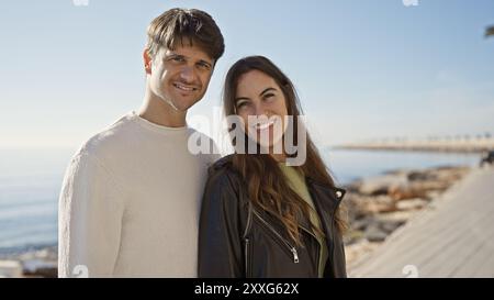 Heureux couple profitant d'une promenade en bord de mer le long de la promenade de l'océan ensemble à la lumière du jour. Banque D'Images