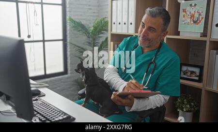 Homme hispanique d'âge moyen vétérinaire dans une clinique vétérinaire avec deux chihuahuas assis sur ses genoux, écrivant sur un presse-papiers. Banque D'Images