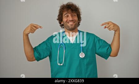 Jeune homme dans des maquillages verts avec un stéthoscope souriant et se pointant sur un fond blanc isolé Banque D'Images