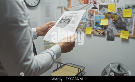 Mature Man analyse un rapport de crime à l'intérieur du bureau d'un détective avec un panneau de preuve en arrière-plan. Banque D'Images