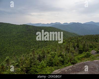 Vue imprenable depuis le sommet de Cascade Mountain, Lake Placid, présentant des rochers escarpés au premier plan et l'immense paysage forestier des Adirondacks Banque D'Images