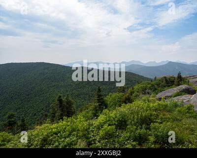 Vue imprenable depuis le sommet de Cascade Mountain, Lake Placid, présentant des rochers escarpés au premier plan et l'immense paysage forestier des Adirondacks Banque D'Images