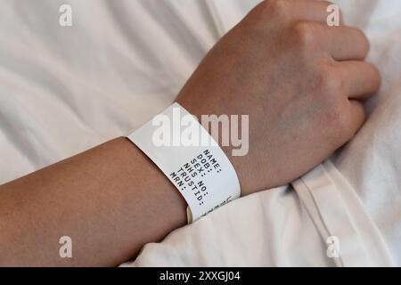 Bras d'une jeune femme portant un bracelet patient avec des données personnelles, hôpital de Basingstoke, Royaume-Uni. Concept : temps d'attente, violation de données, NHS, soins de santé Banque D'Images