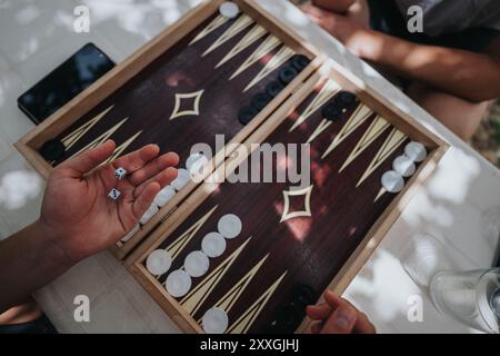 Les mains roulent des dés dans la configuration de jeu de backgammon en plein air Banque D'Images