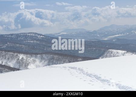 Ligne d'empreintes de pas menant au paysage hivernal de crête de montagne enneigée dans Hokkaido Japon Banque D'Images