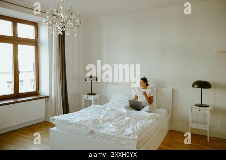 Une chambre confortable le matin avec un ordinateur portable et une lumière naturelle abondante Banque D'Images