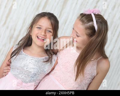 portrait de deux jolies filles preteen joyeuses dans des robes élégantes sur fond clair Banque D'Images