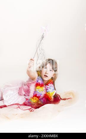 Petite fille joue à la fée dans un costume rose et une baguette magique Banque D'Images