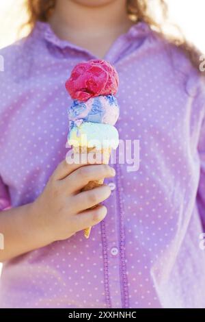 Petite fille qui tient un cône de crème glacée dans ses mains à l'extérieur Banque D'Images