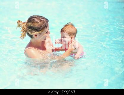 Jeune femme s'amuser avec bébé dans la piscine. Vacances d'été de la famille concept Banque D'Images