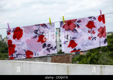 Deux housses d'oreiller à imprimé floral blanc accrochées à une corde à linge pour sécher sur le toit d'un bâtiment au Bangladesh. Banque D'Images