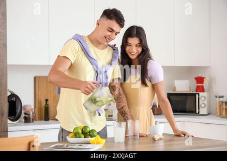 Heureux jeune couple versant du mojito frais dans des verres dans la cuisine Banque D'Images