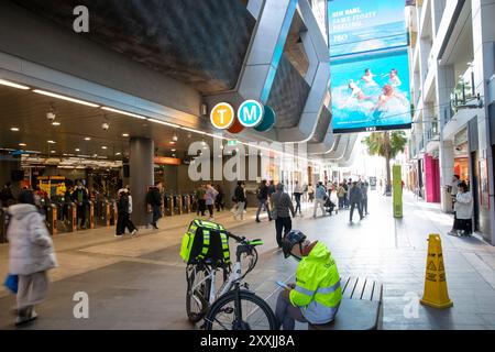 Uber mange les coureurs de livraison prennent une pause à côté de Sydney Chatswood transport station and Interchange, Sydney, NSW, Australie Banque D'Images