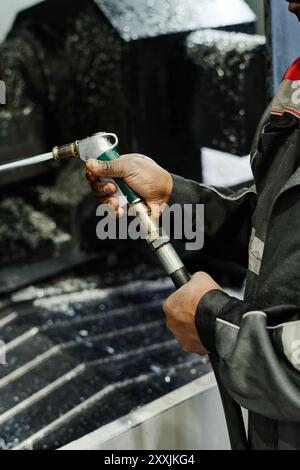 Travailleur exploitant une machine de découpe industrielle dans l'installation de production, manipulant les machines avec précision et soin, portant des vêtements et des gants de protection, en maintenant l'accent sur la tâche à accomplir Banque D'Images