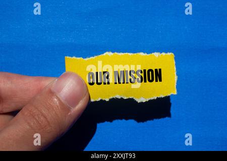 Notre message de mission écrit sur du papier jaune déchiré déchiré avec un fond bleu. Conceptuel notre symbole de mission. Copier l'espace. Banque D'Images