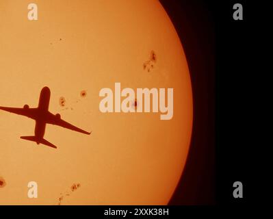 Londres Heathrow départ d'avions traversant le soleil le 25 août 2024. La surface solaire est parsemée de grandes taches solaires. Image traitée à partir de captures vidéo. Banque D'Images