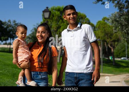 Jeune père et mère latins avec leur bébé de 1 an à l'extérieur par une journée ensoleillée Banque D'Images