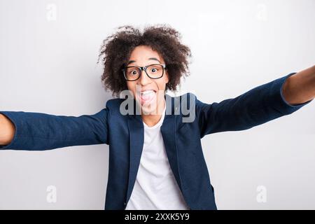 Quelques photos folles de moi ! Beau jeune homme africain faisant selfie tout en se tenant debout sur fond gris Banque D'Images