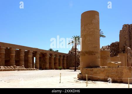 Les visiteurs se promènent dans le complexe du temple de Karnak en Égypte, admirant les colonnes impressionnantes et les anciennes statues de sphinx le long de la route festive bordée wi Banque D'Images