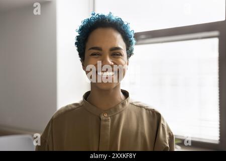 Femme africaine avec les cheveux bleus bouclés courts posant à l'intérieur Banque D'Images