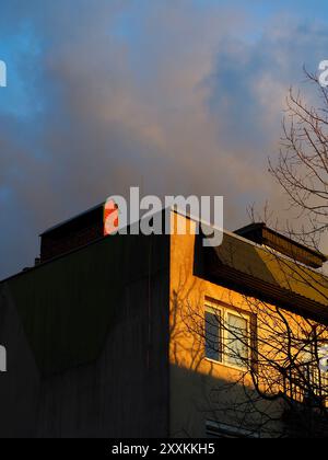 Les rayons dorés du soleil couchant projettent une lueur chaude sur la façade d'un bâtiment urbain, mettant en évidence les détails architecturaux et créant un bel embellissement Banque D'Images