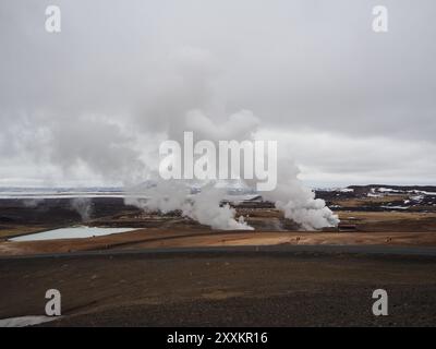 Cette image représente un paysage désolé avec de la vapeur s'élevant des évents géothermiques, capturant la puissance brute et la beauté naturelle de l'énergie géothermique dans un Banque D'Images