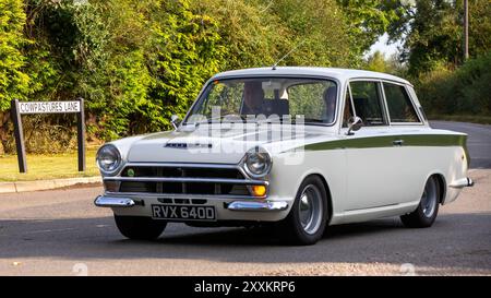 Whittlebury, Northants., Royaume-Uni - 25 août 2024 : 1966 voiture blanche Ford Cortina conduisant sur une route de campagne britannique. Banque D'Images