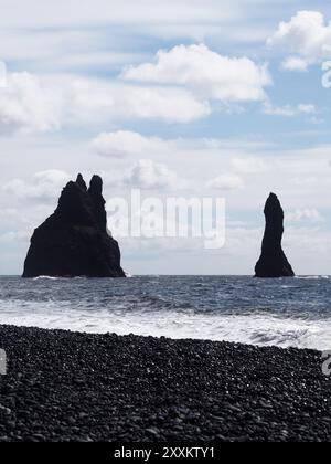 Cette image montre des piles de mer emblématiques posées contre l'océan et le ciel lumineux, avec des vagues s'écrasant à leur base, évoquant un sentiment de force et le mag Banque D'Images