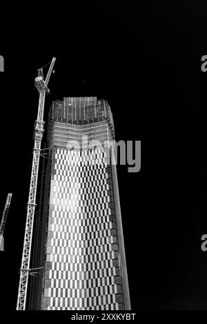 Une photo en noir et blanc d'un grand bâtiment moderne en construction la nuit. Banque D'Images