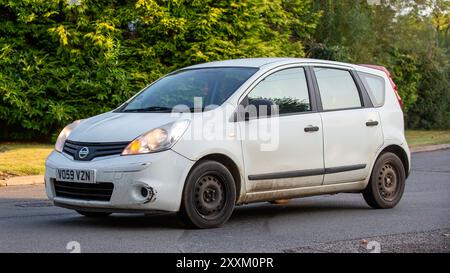 Whittlebury, Northants., Royaume-Uni - 25 août 2024 : 2009 blanc Nissan Note voiture diesel conduite sur une route de campagne britannique. Banque D'Images