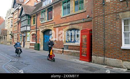 Jeune femme sur un scooter et vélo cycliste devant l'entrée du Story Museum sur Pembroke Street dans la ville d'Oxford Angleterre UKKATHY DEWITT Banque D'Images