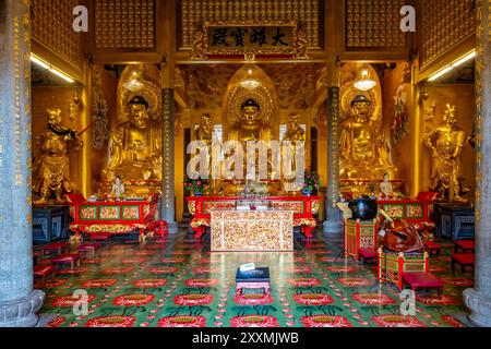 Trois statues dorées de Bouddha sont assis derrière un autel dans un sanctuaire au temple bouddhiste Tek Lok si à George Town, Penang, Malaisie Banque D'Images