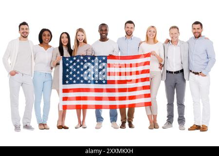 Team of America. Toute la longueur du groupe diversifié heureux de personnes se liant les uns aux autres et tenant le drapeau de l'Amérique tout en se tenant contre backgroun blanc Banque D'Images