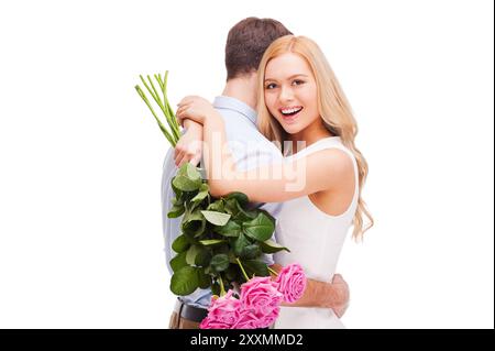 Je l'aime tellement ! Beau jeune couple aimant embrassant tandis que femme tenant un bouquet de roses roses roses et souriant et les deux debout isolé sur BA blanc Banque D'Images