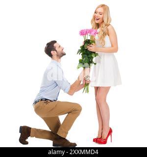 Ils sont aussi beaux que toi ! Pleine longueur de l'homme debout à son genou et donnant un bouquet de roses roses alors que les deux isolés sur fond blanc Banque D'Images