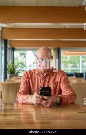 Homme finlandais senior utilisant le téléphone portable dans le restaurant pendant le concept d'automne Banque D'Images