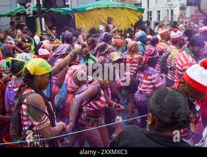 Londres, Royaume-Uni. 25 août 2024. Les fêtards habillés en personnage de livre de puzzle pour enfants Wally pulvérisent de la peinture colorée et de la poudre sur eux-mêmes et les spectateurs. Crédit : Vuk Valcic/Alamy Live News Banque D'Images