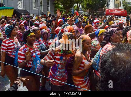 Londres, Royaume-Uni. 25 août 2024. Les fêtards habillés en personnage de livre de puzzle pour enfants Wally pulvérisent de la peinture colorée et de la poudre sur eux-mêmes et les spectateurs. Crédit : Vuk Valcic/Alamy Live News Banque D'Images