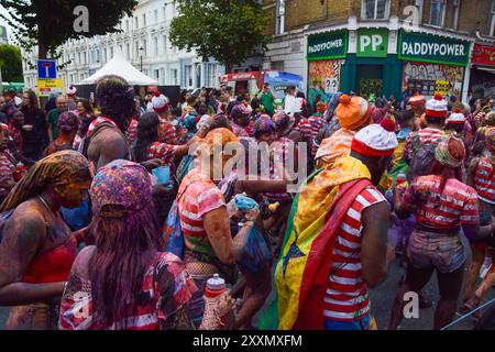 Londres, Royaume-Uni. 25 août 2024. Les fêtards habillés en personnage de livre de puzzle pour enfants Wally pulvérisent de la peinture colorée et de la poudre sur eux-mêmes et les spectateurs. Crédit : Vuk Valcic/Alamy Live News Banque D'Images