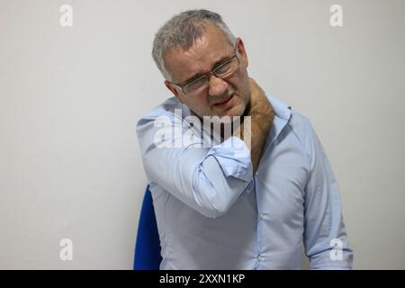 Douleur cervicale. Homme mûr malheureux souffrant de douleurs au cou au bureau Banque D'Images