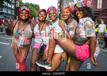 Londres, Royaume-Uni. 25 août 2024. Un groupe de dames profite de leur temps au carnaval couvert de peintures brillantes dans le cadre des célébrations du mas de J'ouvert, une tradition du carnaval des Caraïbes en particulier à Trinidad. L'habituel dimanche matin J'ouvert a été annulé, mais les fêtards ont encore célébré plus tard. Le dimanche du carnaval de Notting Hill a commencé avec le traditionnel carnaval des enfants aujourd'hui et plus tard, les fêtards ont célébré le week-end des vacances bancaires en participant ou en regardant le long de la route du carnaval, dans les systèmes de sonorisation, les stands et les lieux. Crédit : Imageplotter/Alamy Live News Banque D'Images