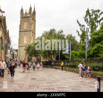 Les gens qui font du shopping et des touristes le long de Trinity Street dans la capitale galloise Cardiff avec une vue sur St John the Baptist City Parish Church. Banque D'Images