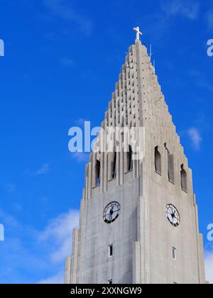 Reykjavik, Islande - 9 mai 2024 : une imposante structure d'église blanche Hallgrimskirkja avec une croix sur le dessus se dresse bien en évidence contre un bleu vif s. Banque D'Images