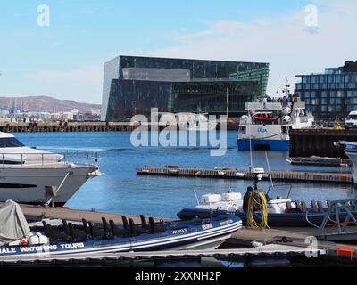 Reykjavik, Islande - 9 mai 2024 : une scène portuaire moderne avec des yachts élégants amarrés près d'un bâtiment frappant aux motifs géométriques colorés, Under Banque D'Images