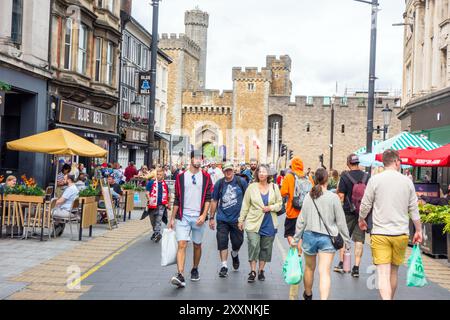 Les gens apprécient le temps chaud shopping le long de la rue High dans la capitale galloise de Cardiff avec une vue sur le château de Cardiff Banque D'Images